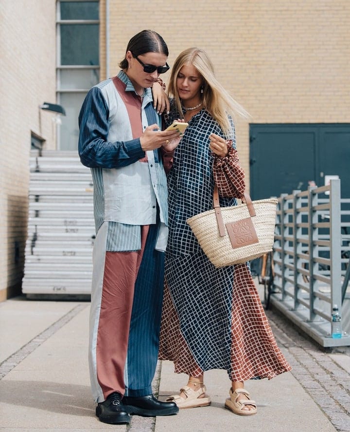 Models look onto a phone during Copenhagen FW