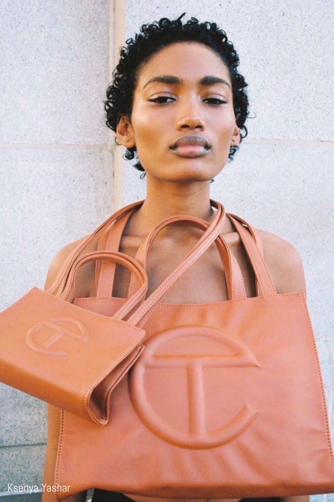 Model poses with two Telfar shopping bags around her neck